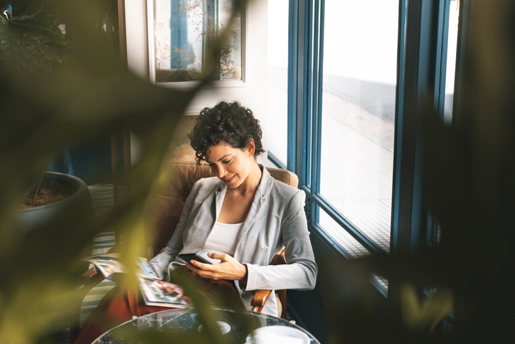 A business woman smiles while she reads an email on her phone in a hotel lobby