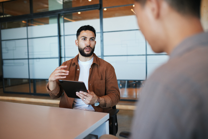 A man asking another man a question in a modern office setting